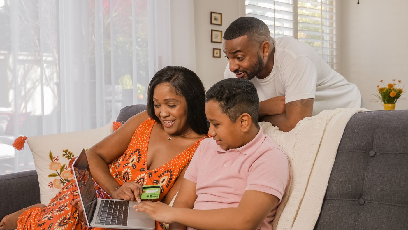 Parents and their son looking at a laptop together. Photo on Pexels.